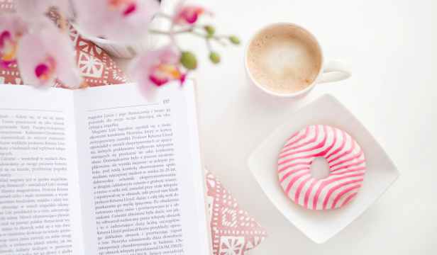 a book cup of coffee and flavoured donut on square white ceramic bowl